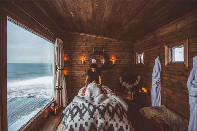 A person receiving a message wrapped in blankets in a cozy wood-sided room with a view of water outs